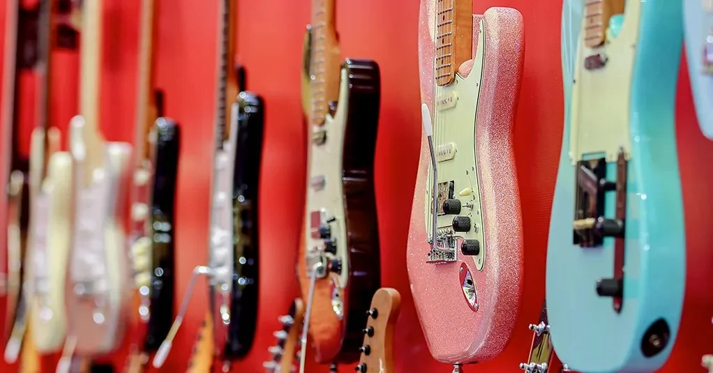 Sélection de guitares électriques exposées sur fond rouge